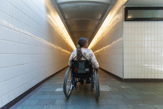 Woman with spinal cord injury in a wheelchair accessing subway train station