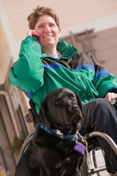 Woman with multiple sclerosis talking on a mobile phone with a service dog