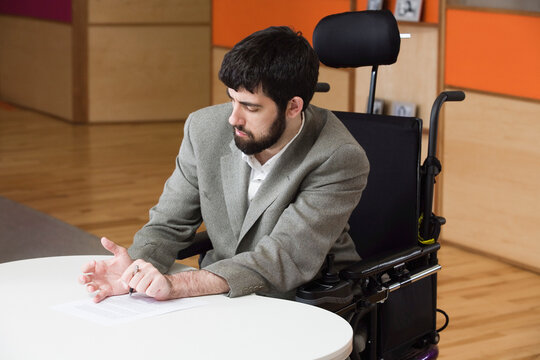 Mature man with cerebral palsy signing a document