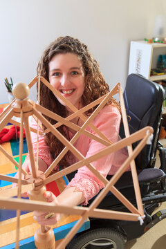 Woman with Muscular Dystrophy working with her umbrella yarn winder on her power chair
