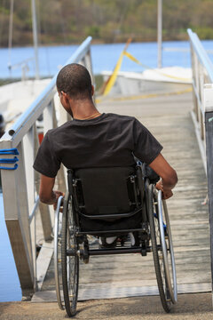 Man in a wheelchair who had Spinal Meningitis going down a ramp to a dock