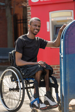 Man in a wheelchair who had Spinal Meningitis using the public mail box