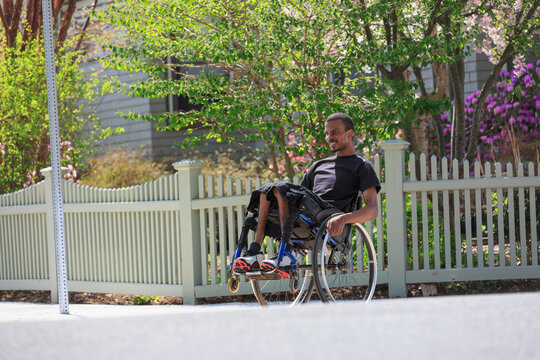 Man in a wheelchair who had Spinal Meningitis in a neighborhood leaning on his wheels