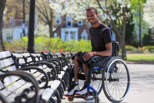 Man in a wheelchair who had Spinal Meningitis sitting near a park bench