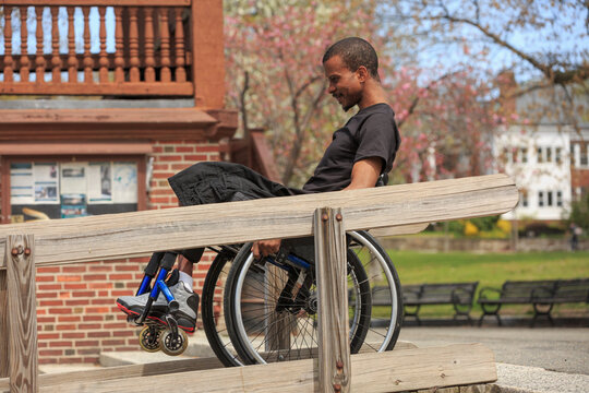 Man in a wheelchair who had Spinal Meningitis using a public building ramp
