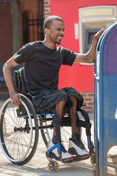 Man in a wheelchair who had Spinal Meningitis using the public mail box