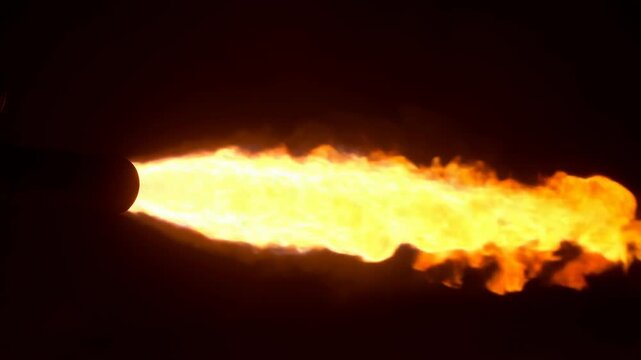 Static shot of a flamethrower shooting a massive burst of fire and smoke on a dark background