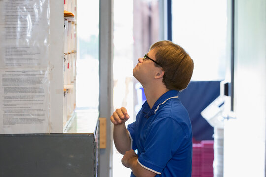 Young man with Down Syndrome filing mail while working in a health clinic
