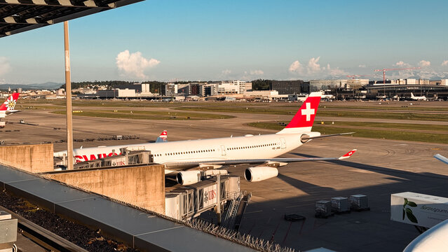 Zurich, Switzerland - May 29, 2025: Planes parked at Zurich Airport with clear sky and terminal view in the afternoon light