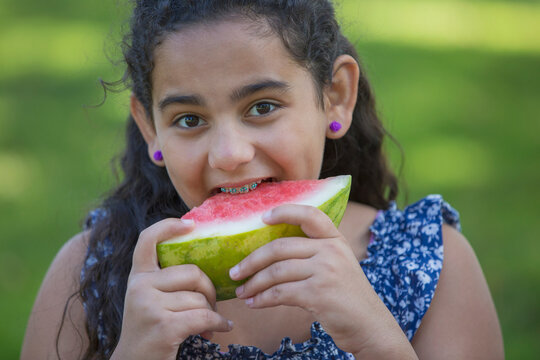 Portrait of happy Hispanic teen girl with braces eating watermelon