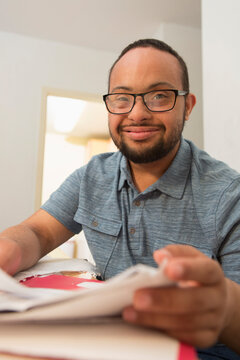 Happy African American man with Down Syndrome doing paperwork at home