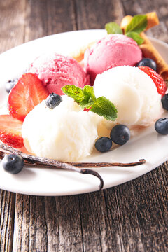 vanilla and strawberry ice cream scoops with fresh berries on plate