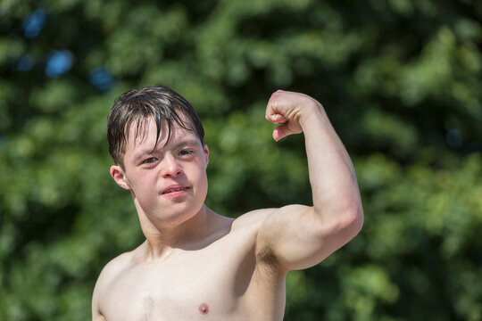 Portrait of young man with Down Syndrome showing his bicep on a dock