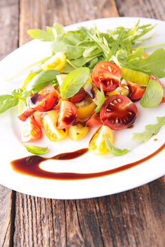 tomato salad with arugula and balsamic glaze drizzle on plate
