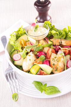grilled chicken salad with fresh vegetables and dressing in bowl