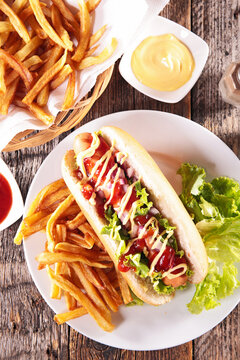 hot dog with french fries and mustard ketchup drizzle on plate