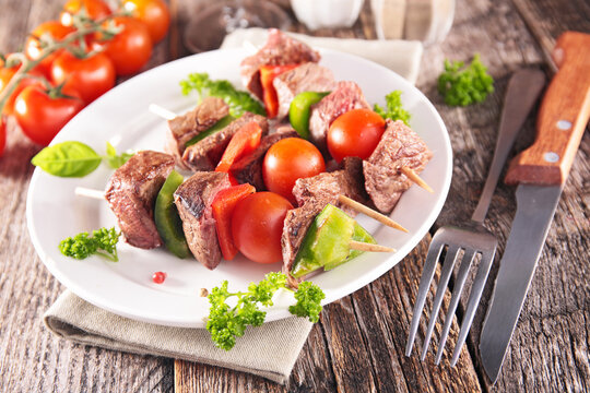 beef skewers with grilled vegetables and cherry tomatoes on plate
