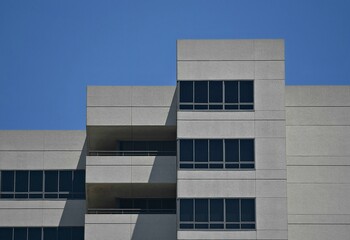 Cityscape with scenic view of a commercial high-rise building symmetrical  grey concrete facade with glass windows. © ELENI MAVRANDONI