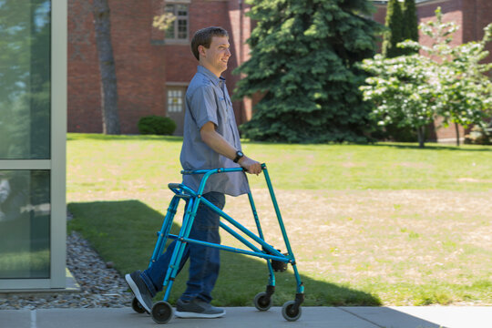 Young man with Cerebral Palsy using his walker to walk to work