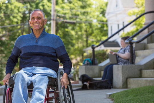 Man with Spinal Cord Injury sitting in wheelchair with his daughter in background who is Blind