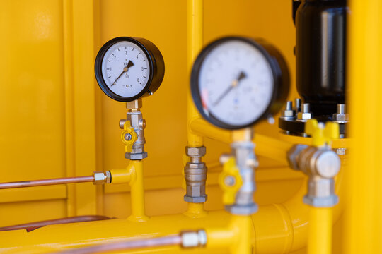 Pressure gauge manometer installed on a yellow gas distribution pipeline close-up.