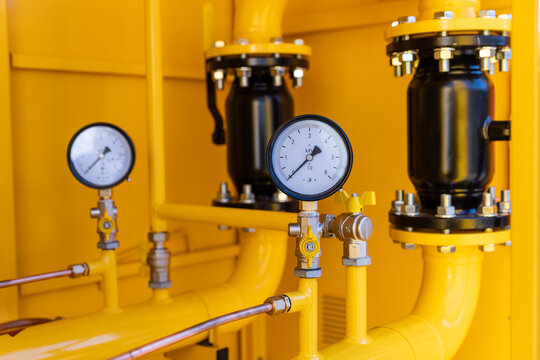 Pressure gauge manometer installed on a yellow gas distribution pipeline close-up.