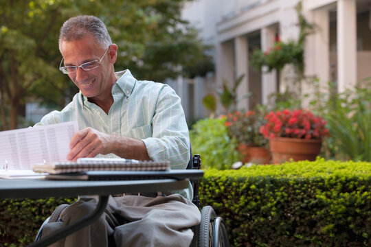 Businessman with spinal cord injury working on documents at a cafa&Atilde;&permil;a