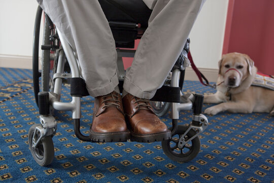 Man with a Spinal Cord Injury in a wheelchair with a service dog waiting for elevator