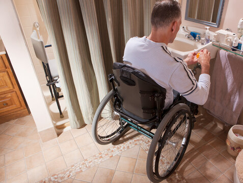 Man with spinal cord injury in a wheelchair looking at a pill bottle