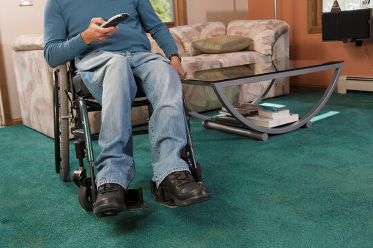 Man with spinal cord injury in a wheelchair using a remote control