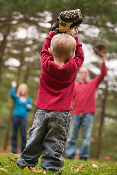Boy playing baseball with his parents and using sign language to communicate