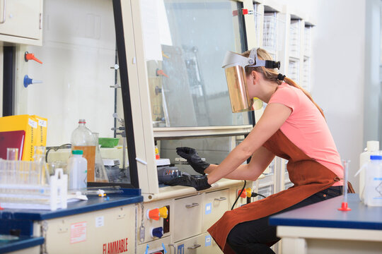 Engineering student wearing protective equipment while working on chemistry experiment in fume hood