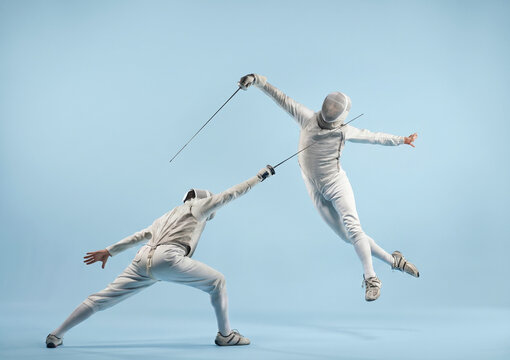 Two fencers in intense duel, one lunging while the other leaps dramatically with foils.