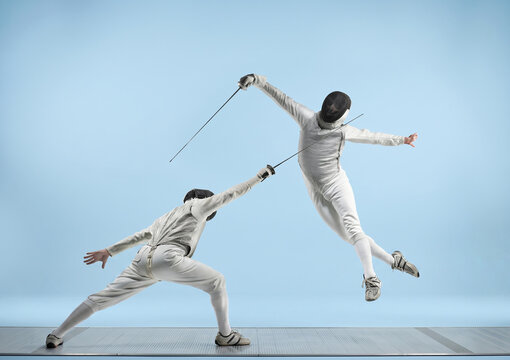Two fencers in intense duel, one lunging while the other leaps dramatically with foils.