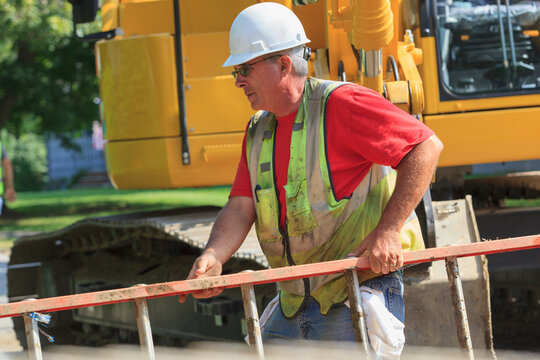 Construction worker on site carrying ladder