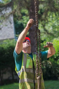 Construction worker guiding chain attached to excavator