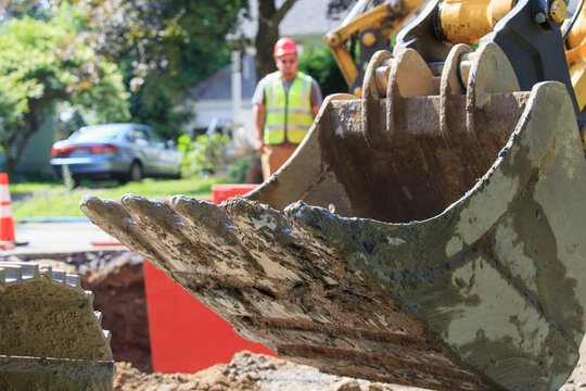 Construction worker watching backhoe bucket