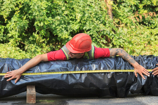 Construction worker measuring length of water main section