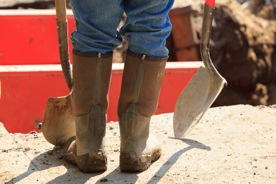 Construction worker preparing to enter shored up hole with shovels