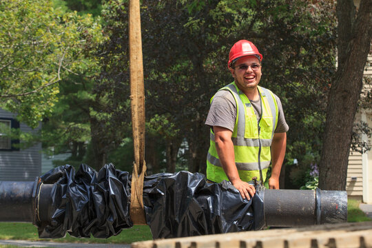 Construction worker guiding water main into place