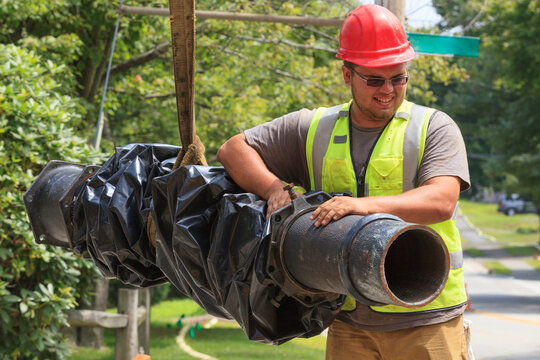 Construction worker guiding water main into place