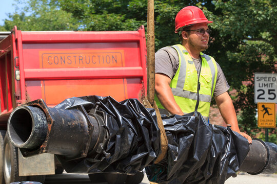 Construction worker guiding water main into place