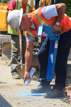 Construction supervisor marking alignment of water main on pavement