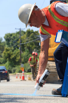 Construction supervisor marking alignment of water main on pavement