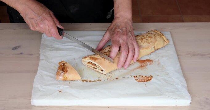 Slicing Baked Jam and Walnut Pastry Roll into Cookies with Bread Knife, Close Up