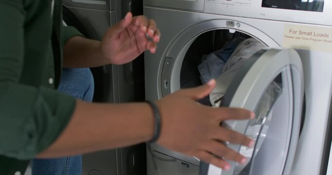 African American man green-shirt holding load loading dryer to dry latching placing bin, copy space