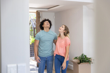Naklejka premium Couple standing together in hallway at open wooden front door unpacking box with potted plant