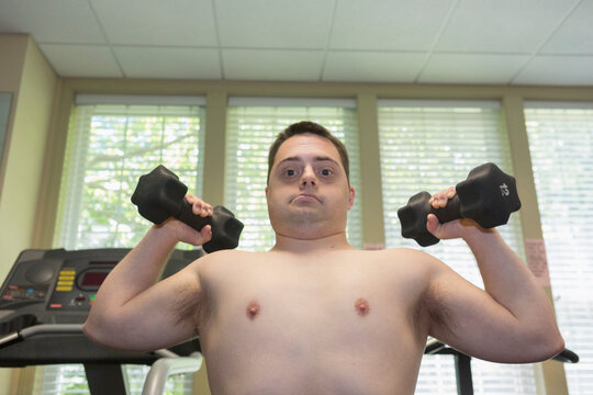 Man with Down Syndrome exercising in a gym with dumbbells