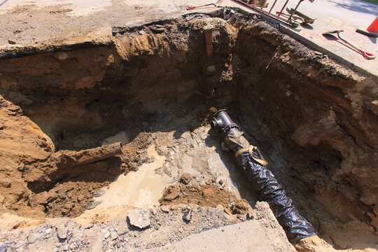 Section of new water main and old piping in street hole
