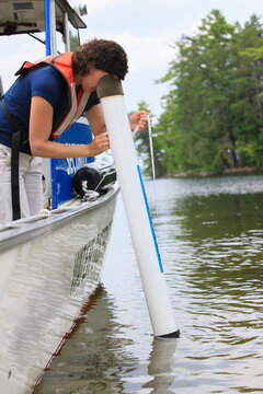 Water treatment engineer using viewing tube to observe water quality turbidity